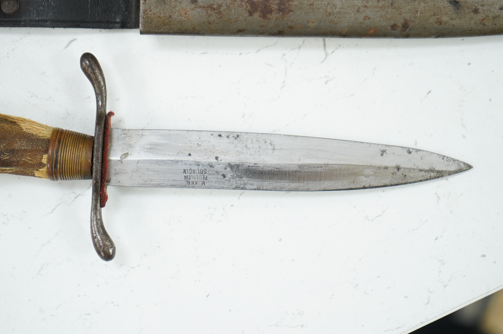 A First World War German Deer Hoof Fighting Knife, with a deer’s hoof grip, brass ferrell and steel cross guard, in original steel scabbard with leather belt loop mount, single edged blade with makers mark to one side; M